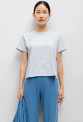 Woman wearing a light gray t-shirt and blue pants against a white background
