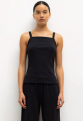 Woman wearing a black sleeveless top and black pants against a white background