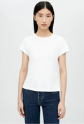 Model wears white crewneck t-shirt with dark wash blue jeans. She stands in front of a white background. 