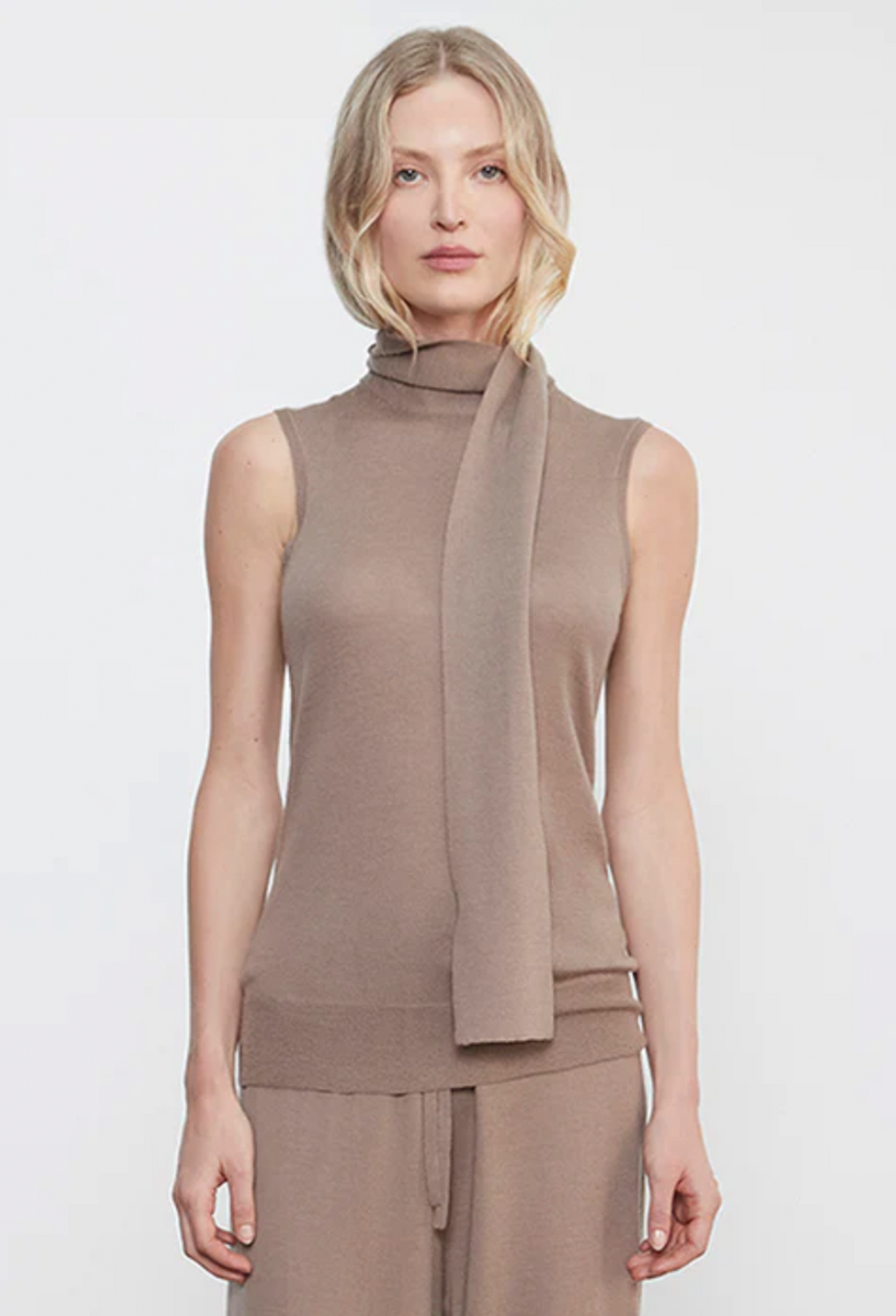 Woman wearing a brown sleeveless top with a scarf on a white background
