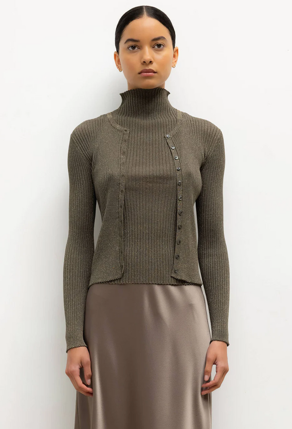 Woman wearing a green ribbed sweater and skirt against a white background
