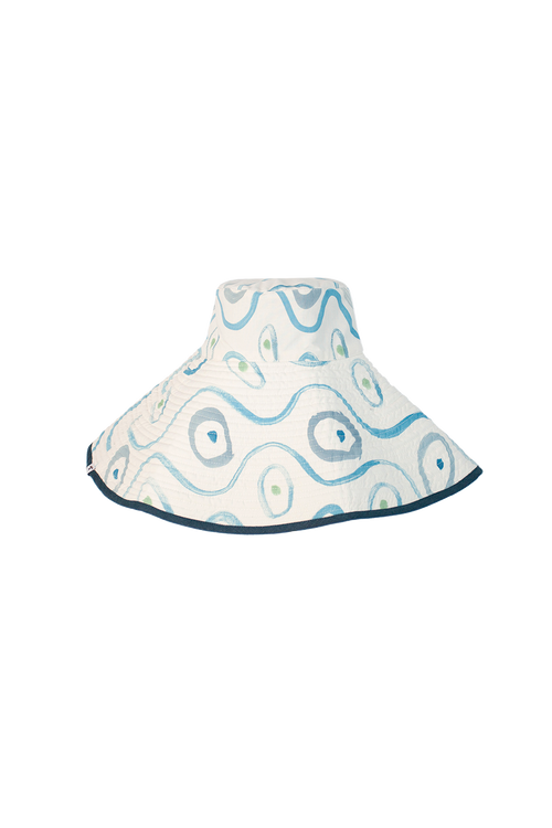 Reversible hand painted bucket hat, white with blue painted designs and blue rim. Set against black checkered background.
